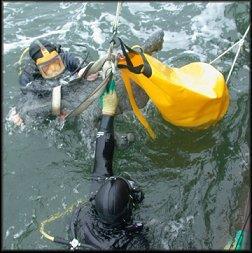 Diver underwater inflating a yellow lift bag
