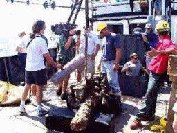 Photo of a dive team recovering artifacts on the deck of a boat