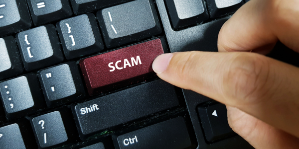 A keyboard with a red return key that says "scam"