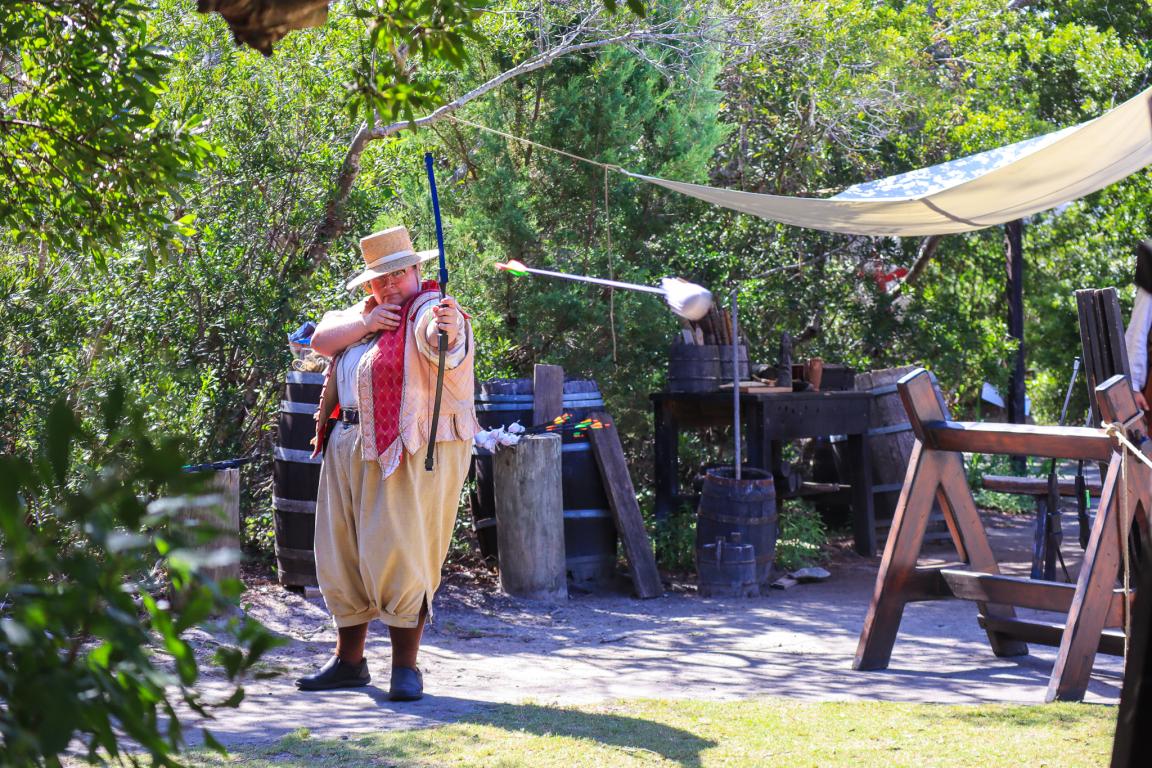 Costumed interpreter shooting an arrow