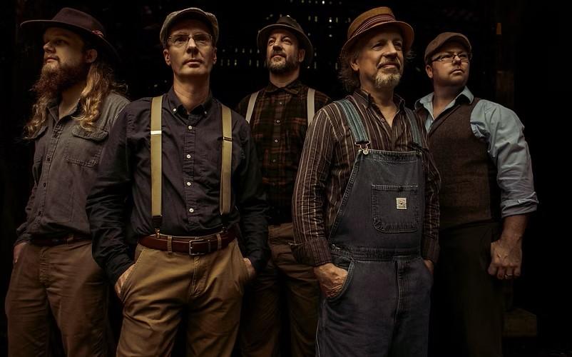 A group of 5 men looking past the camera in in overalls and suspenders