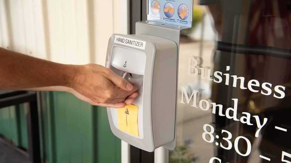 Close-up of hands at a hand sanitizer station.