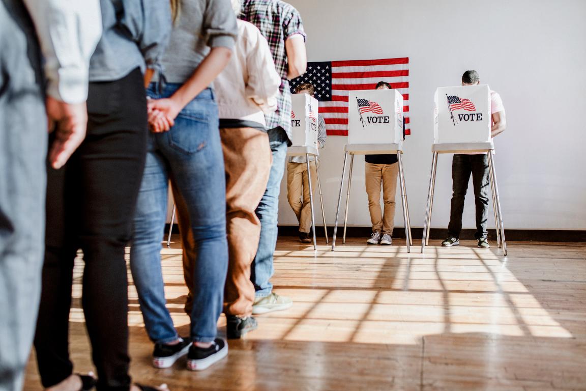 People standing in line to vote in voting booth