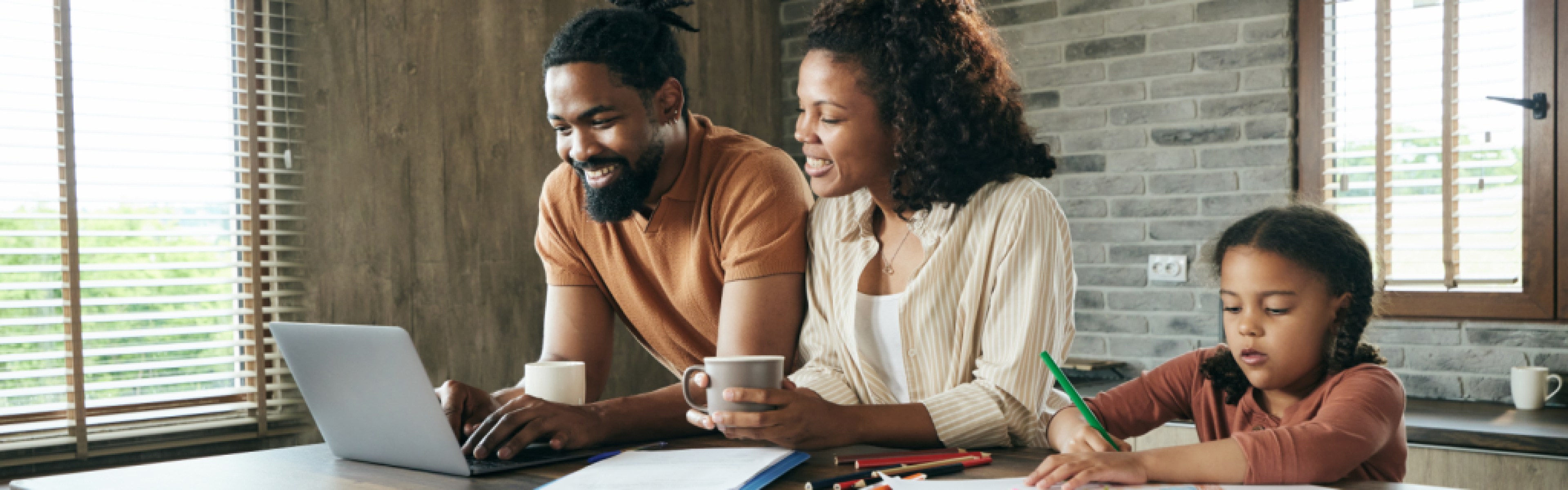 Smiling couple looking at computer while daughter draws beside them