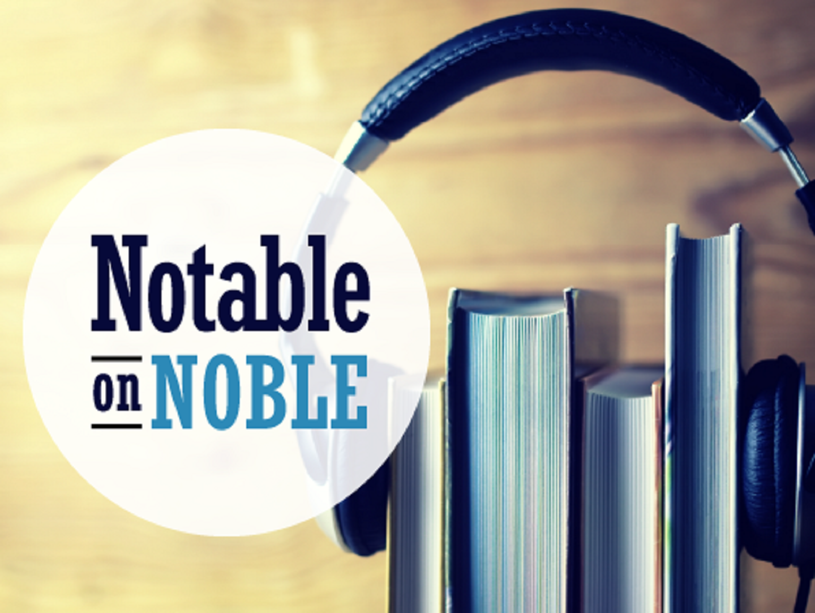 A pair of headphones sit on top of books standing straight up, mimicking ears. The words Notable on NOBLE sit in front