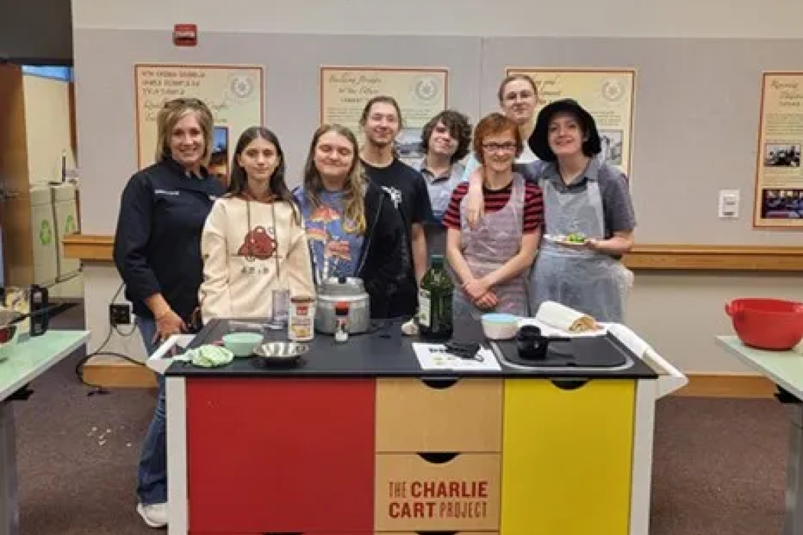 Program leaders and teens are pictured next to a charlie cart during the "Teen Cusine: Chop It Up!" program