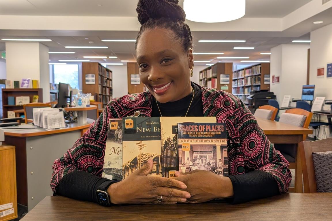 Assistant State Librarian Tiwanna Nevels hugging some of her favorite books