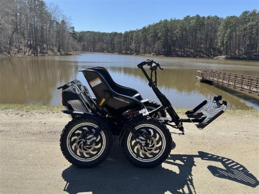 a motorized wheelchair parked in front of a pond on a gravel path