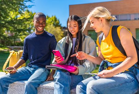 Multi-ethnic students sitting using mobile in the campus